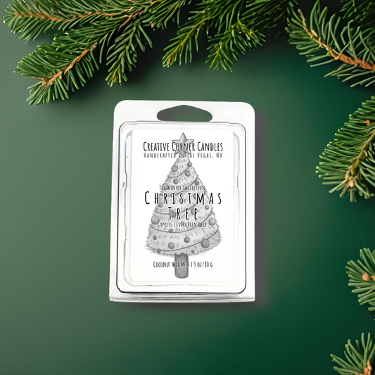 Wax melt packaging with Christmas tree design on a green background with pine branches.