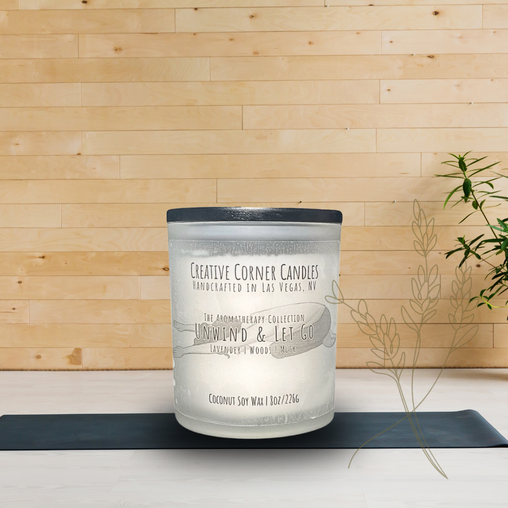 Unwind and Let Go handcrafted candles with a soothing aroma and a label featuring a hand-drawn illustration of a woman doing a child yoga pose