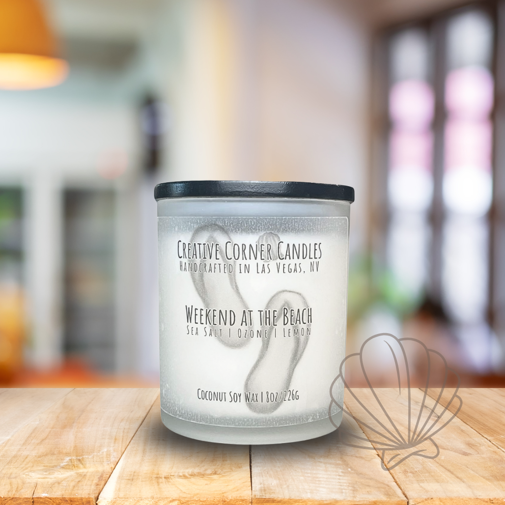 Weekend at the Beach handcrafted candles with a breezy, ocean-inspired scent and a label featuring a hand-drawn illustration of a beach scene
