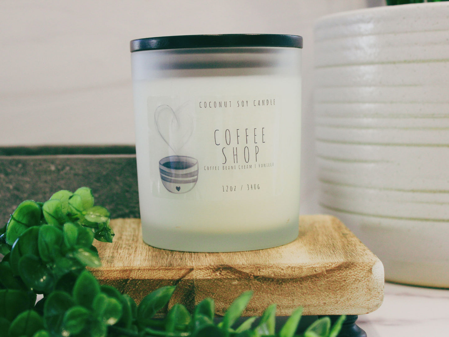 An inviting Coconut Soy Candle named 'Coffee Shop.' The candle is in a stylish glass container, emanating a warm glow. The label features a coffee cup illustration, capturing the essence of a cozy coffee shop. Perfect for creating a comforting atmosphere with rich coffee notes. Ideal for home decor and relaxation. Hand-poured and crafted with premium coconut soy wax for a clean burn. Elevate your space with this aromatic coffee-inspired candle